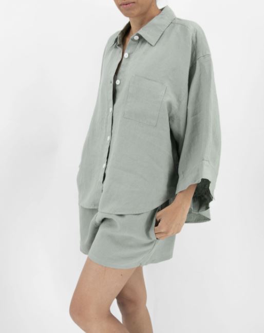 Person wearing a light gray oversized shirt and shorts set on a white background