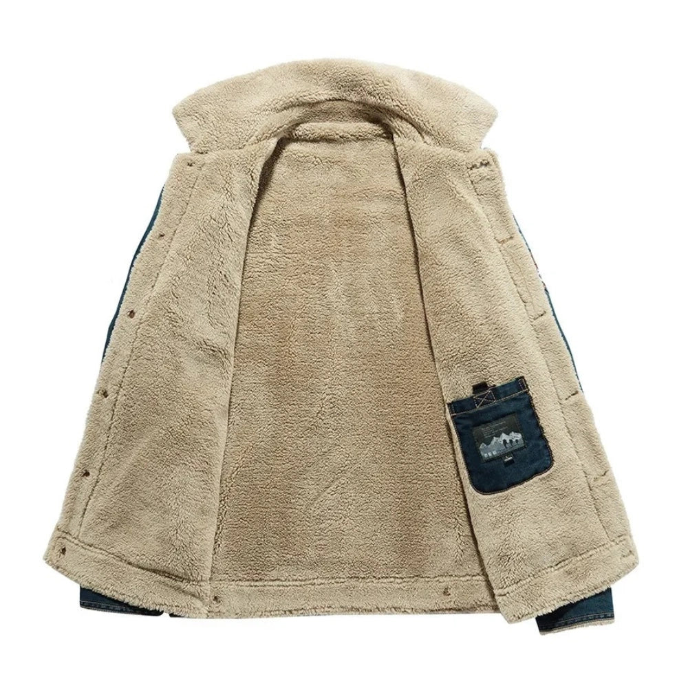 A beige sherpa-lined jacket or vest shown from the back, featuring a soft fleece body, dark blue denim shoulder panels, and a matching denim back pocket with a small embroidered logo.