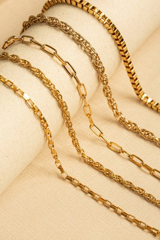 Gold chains on jewelry and watches on a beige fabric